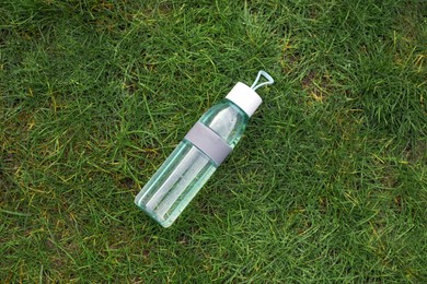 Photo of Bottle of water on green grass, top view. Morning exercise