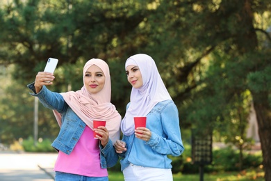 Muslim women in hijabs taking selfie outdoors