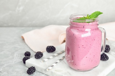 Photo of Delicious blackberry smoothie in mason jar on marble table