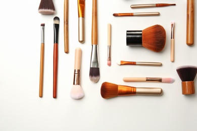 Photo of Flat lay composition with makeup brushes of professional artist on white background