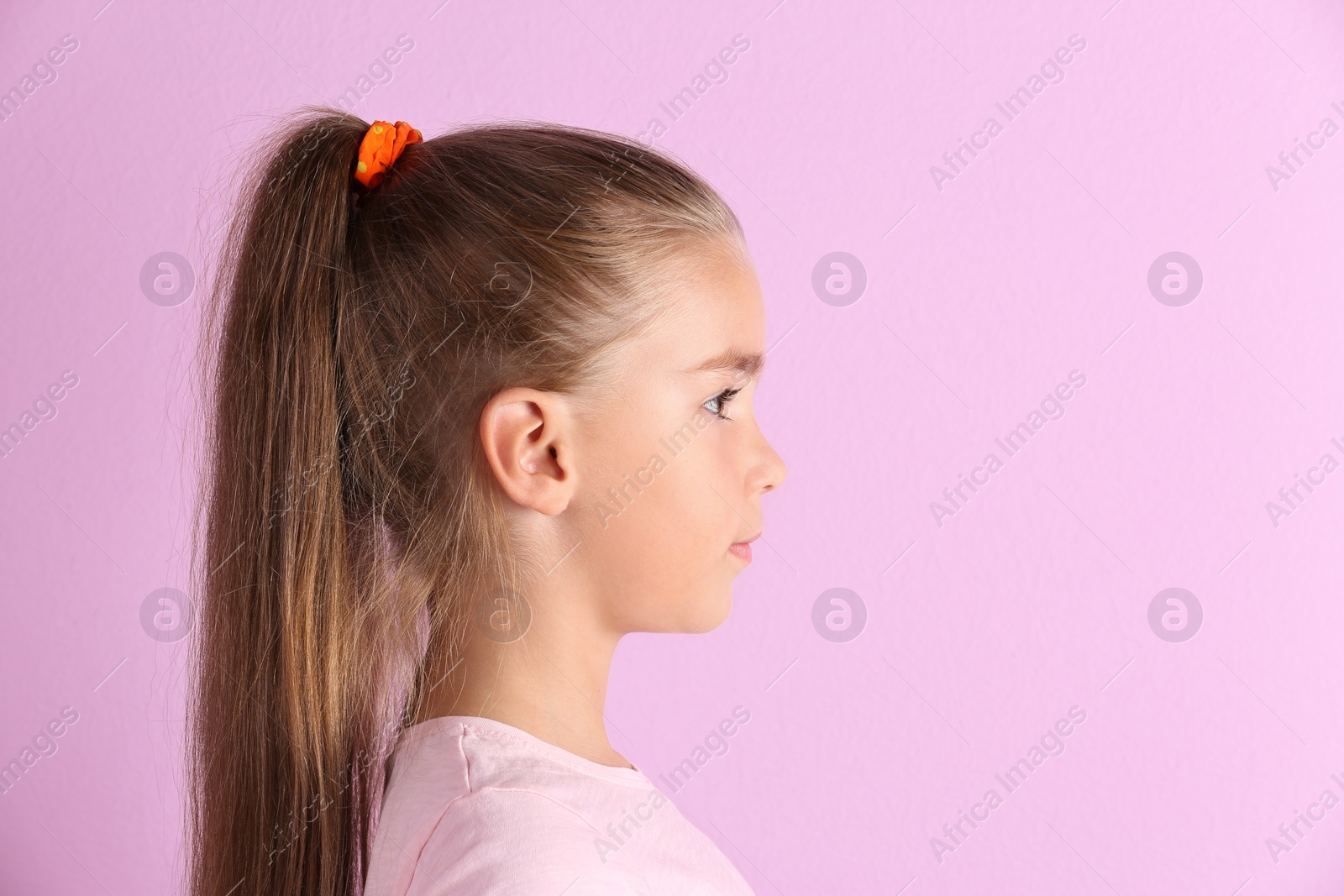 Photo of Cute little girl with hearing problem on color background. Space for text