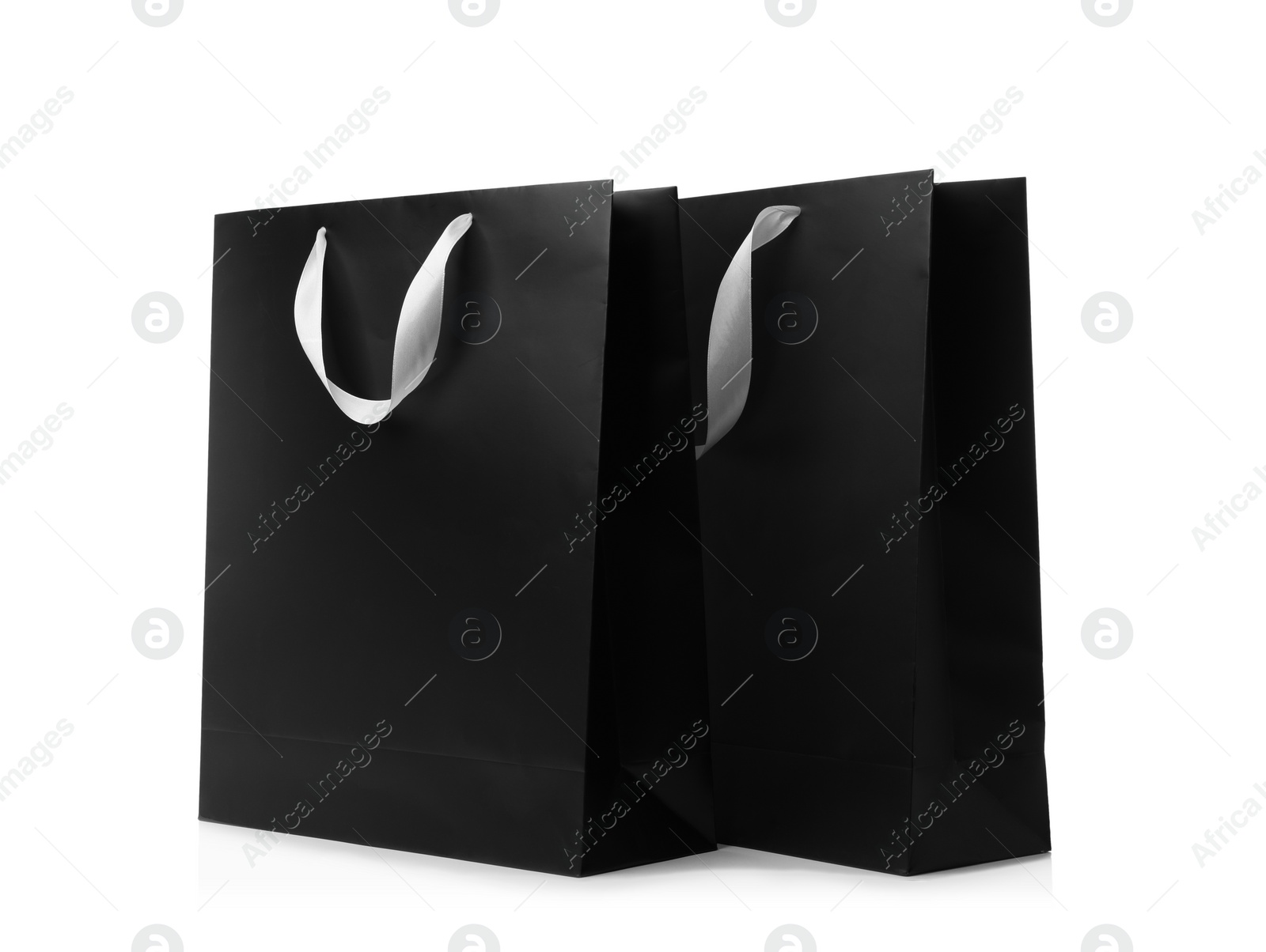 Photo of Paper shopping bags with ribbon handles on white background. Mockup for design