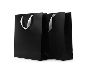 Photo of Paper shopping bags with ribbon handles on white background. Mockup for design