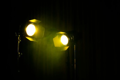 Photo of Bright yellow spotlights on dark stage, space for text