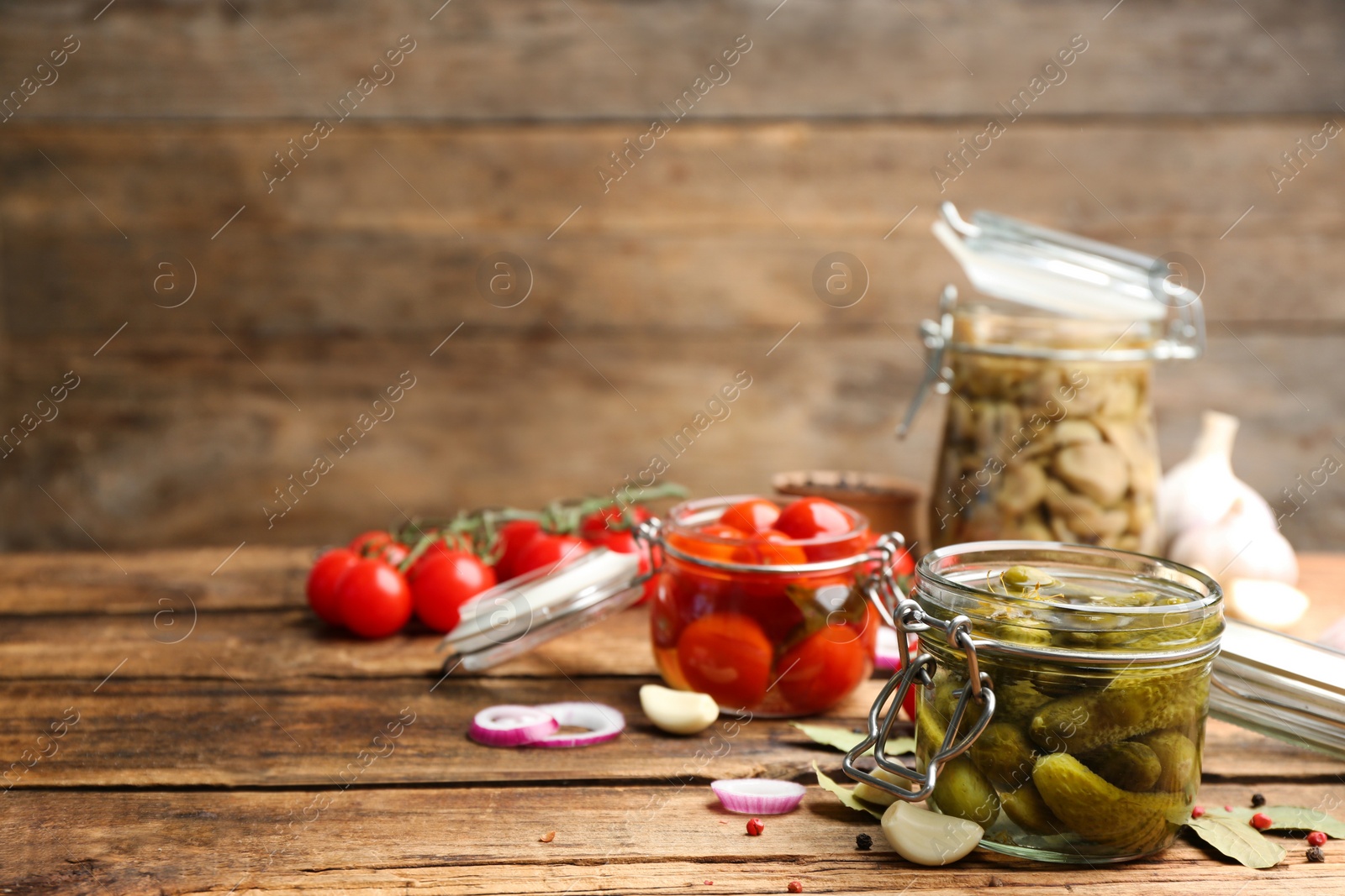 Photo of Glass jar of pickled cucumbers and ingredients on wooden table. Space for text