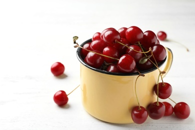 Photo of Mug of delicious cherries on white wooden table, space for text