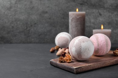 Bath bombs, candles and dry flowers on black table, space for text