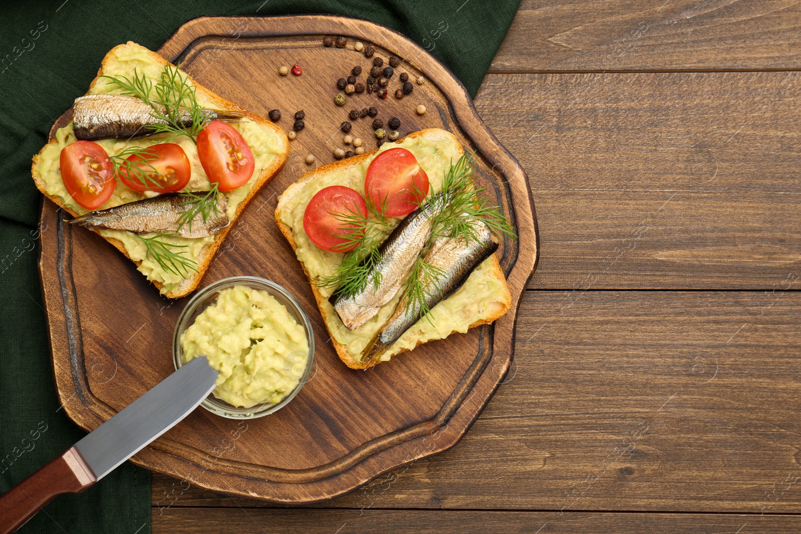 Delicious sandwiches with sprats, tomatoes, dill and avocado puree served on wooden table, top view. Space for text Photo of Delicious sandwiches with sprats, tomatoes, dill and avocado puree served on wooden table, top view. Space for text