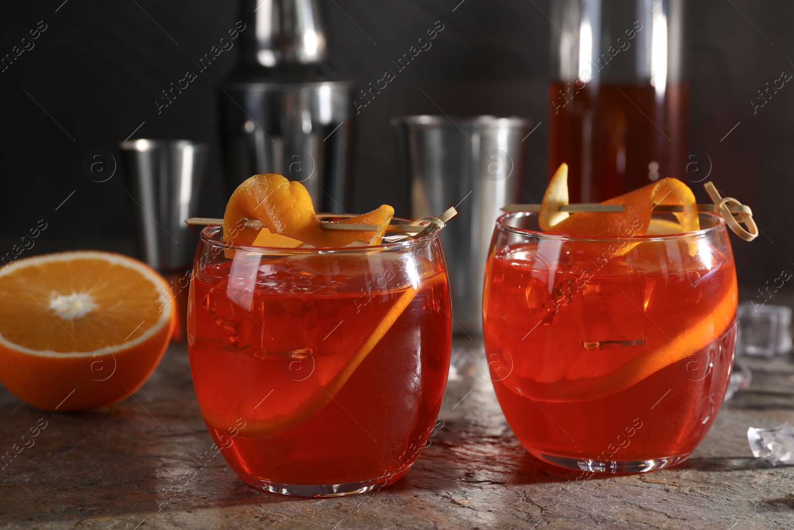 Photo of Aperol spritz cocktail, ice cubes and orange slices in glasses on grey textured table, closeup