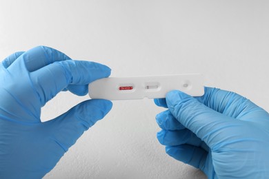 Photo of Doctor holding disposable Covid-19 express test at white table, closeup