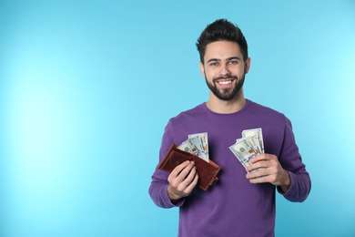 Portrait of happy young man with money on color background. Space for text