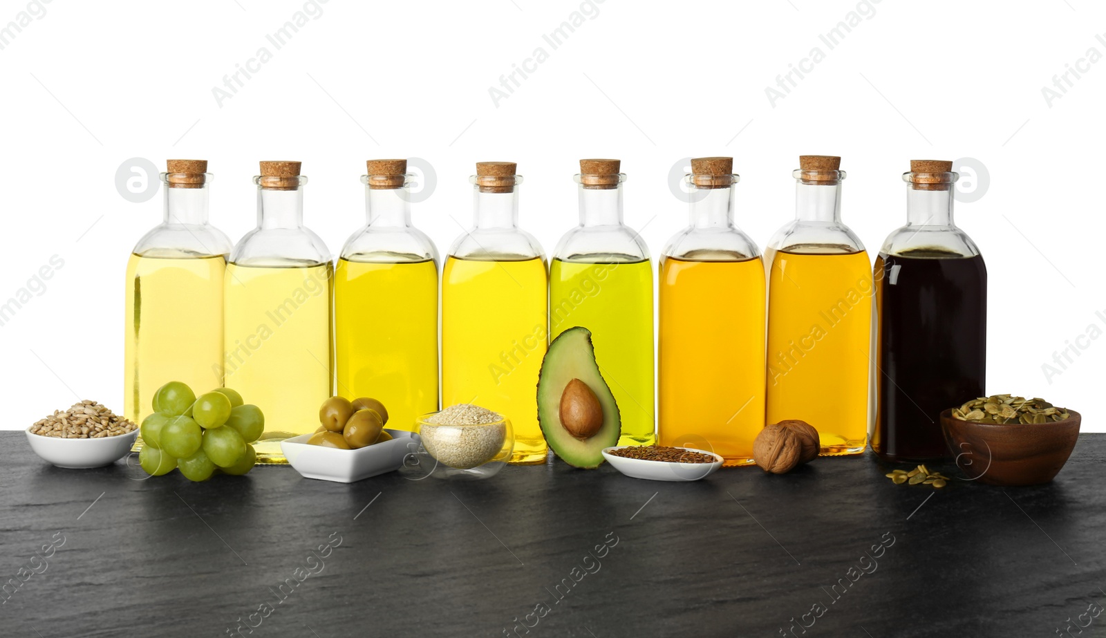 Photo of Vegetable fats. Bottles of different cooking oils and ingredients on wooden table against white background