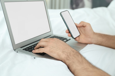 Photo of Man with smartphone and modern laptop at home, closeup