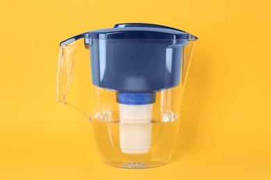 Filter jug with purified water on yellow background