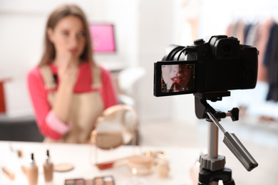 Photo of Beauty blogger filming make up tutorial at home, focus on camera