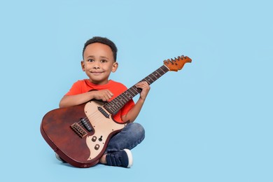 Photo of African-American boy with electric guitar on turquoise background. Space for text