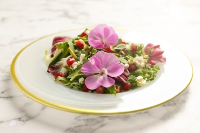 Photo of Fresh spring salad with flowers on white marble table, closeup