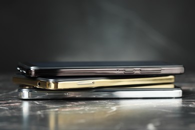 Stack of modern smartphones on black marble table. Space for text