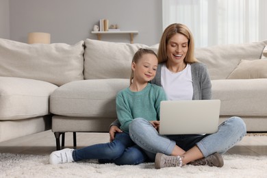 Photo of Happy woman and her daughter with laptop on floor at home