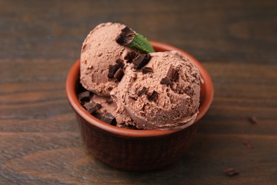 Bowl of tasty ice cream with chocolate chunks on wooden table, closeup