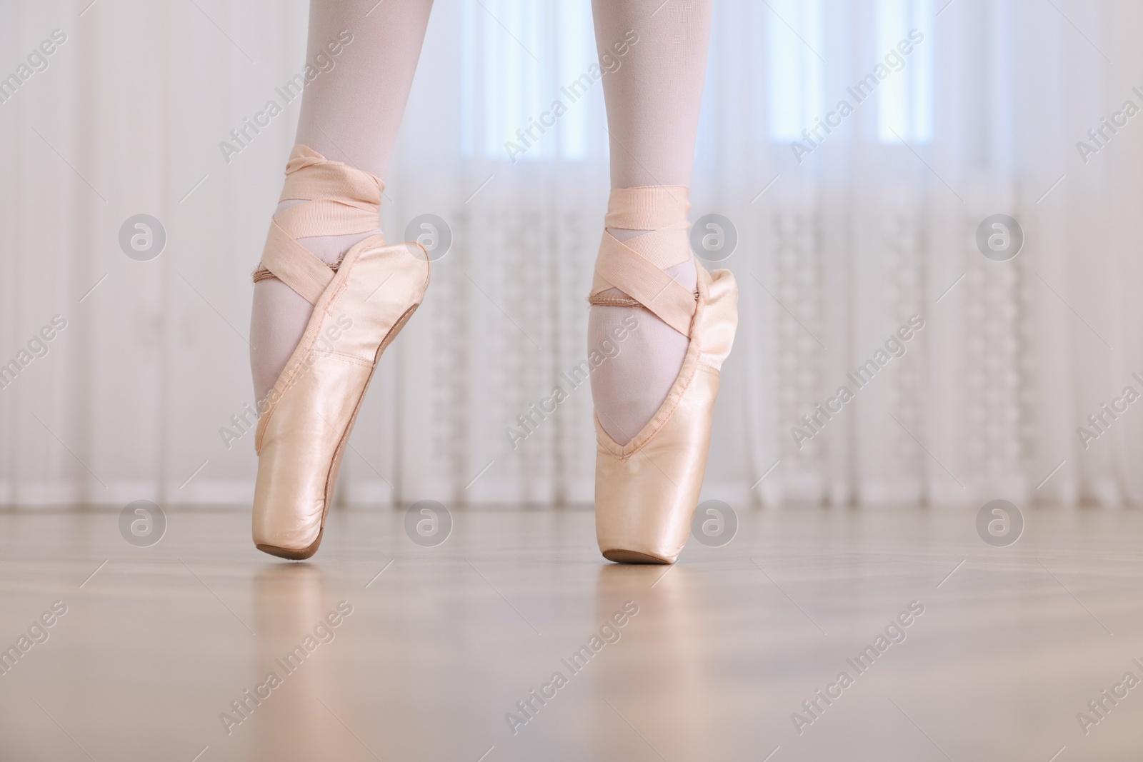 Photo of Little ballerina practicing dance moves in studio, closeup of legs. Space for text