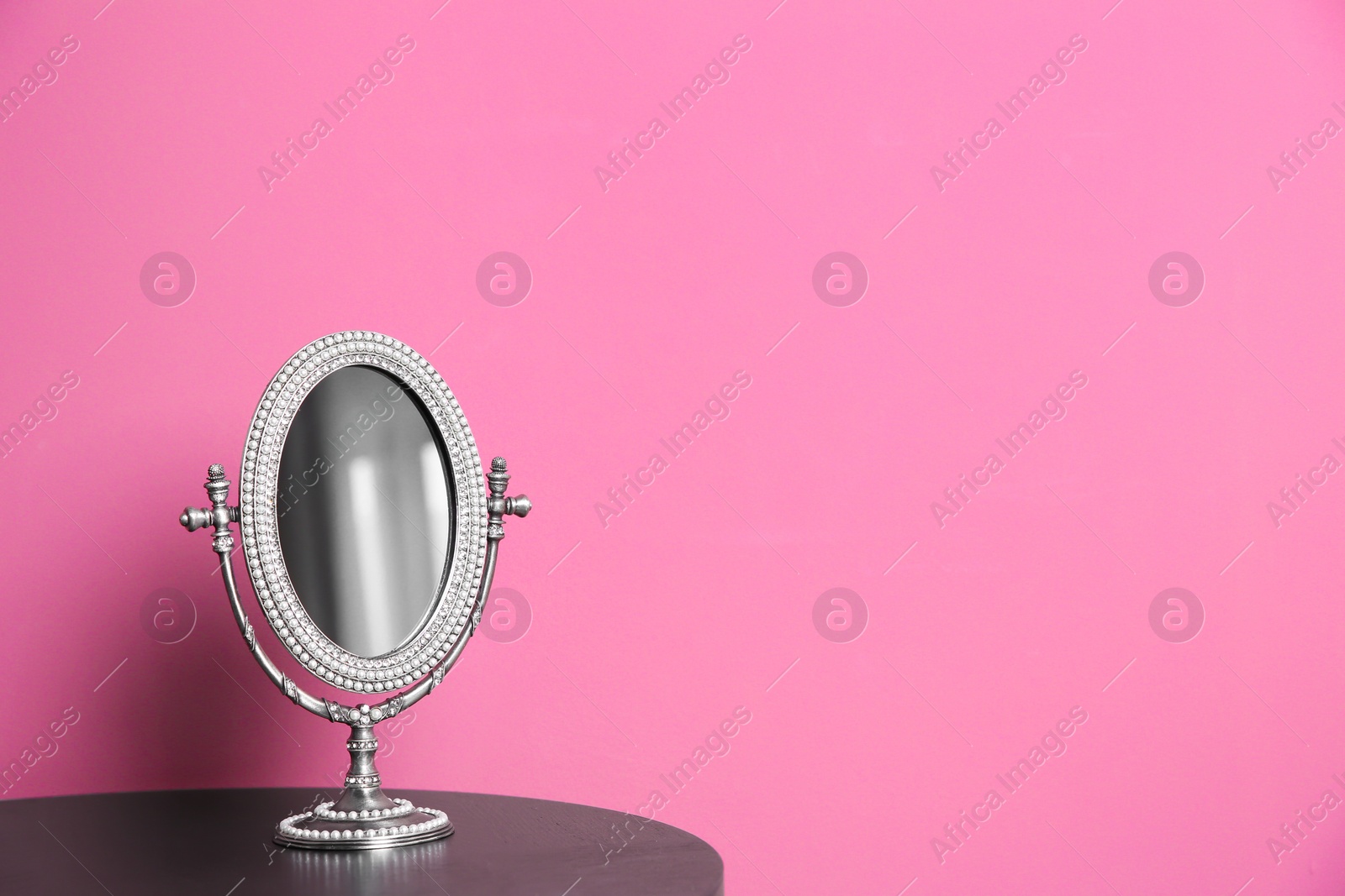 Photo of Stylish mirror on table near color wall