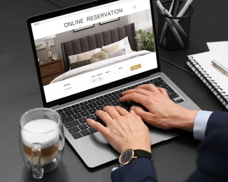 Image of Woman using laptop to book hotel at black table, closeup