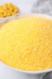 Raw cornmeal in bowl on white table, closeup