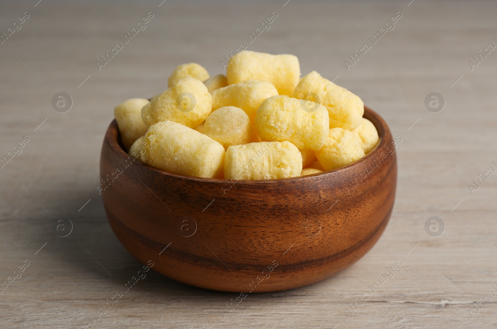 Photo of Bowl of corn sticks on wooden table, closeup