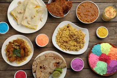 Traditional Indian food and color powders on wooden table, flat lay. Holi festival celebration