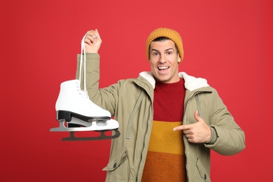 Emotional man with ice skates on red background