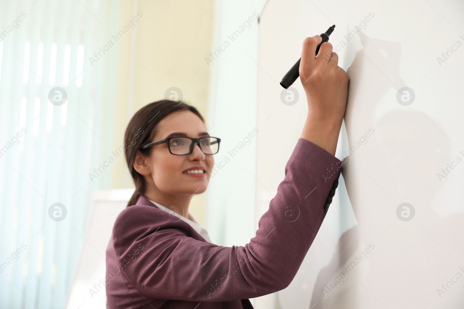 Photo of Female teacher writing on whiteboard in classroom