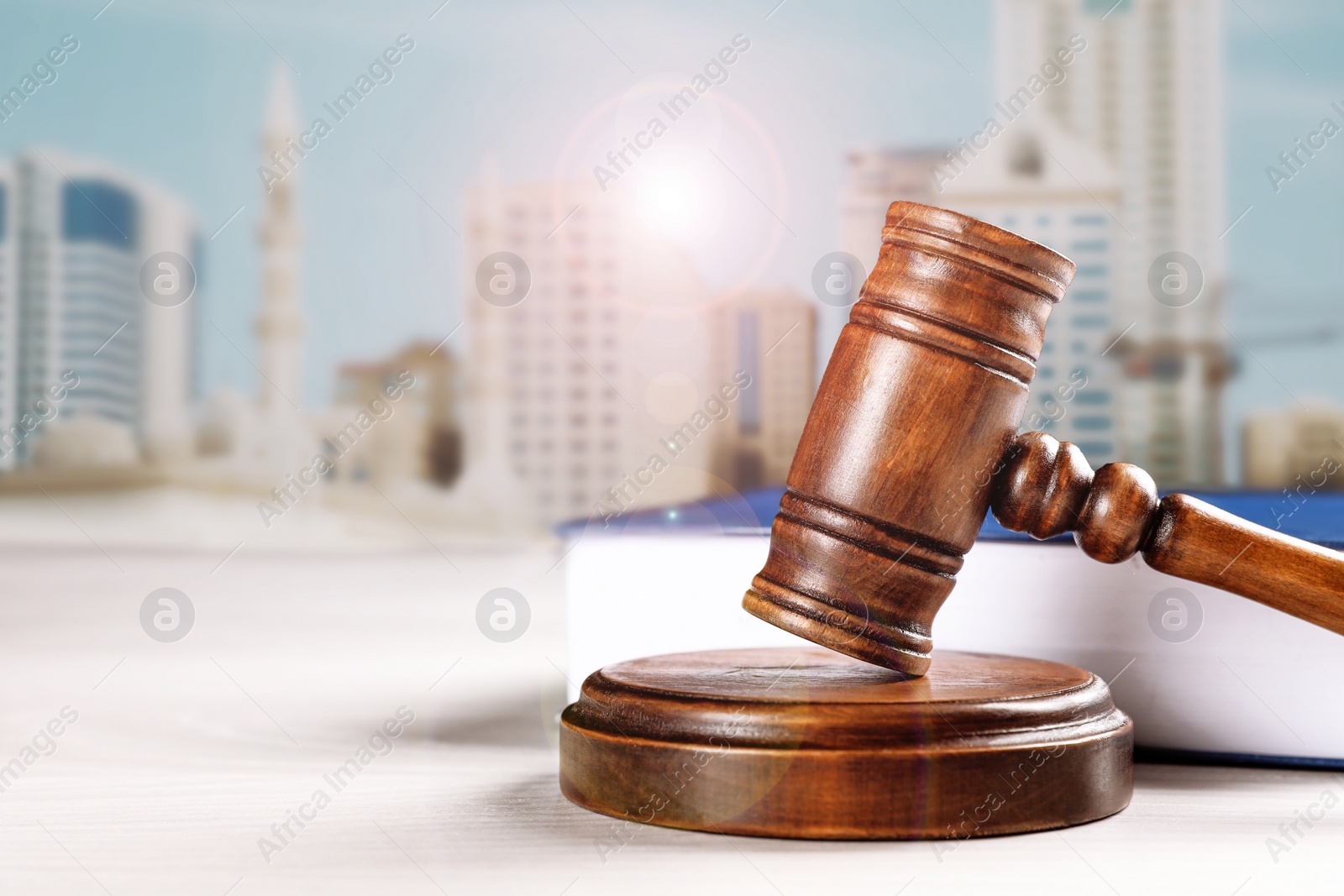 Image of Judge's gavel and book on table against beautiful cityscape, space for text 