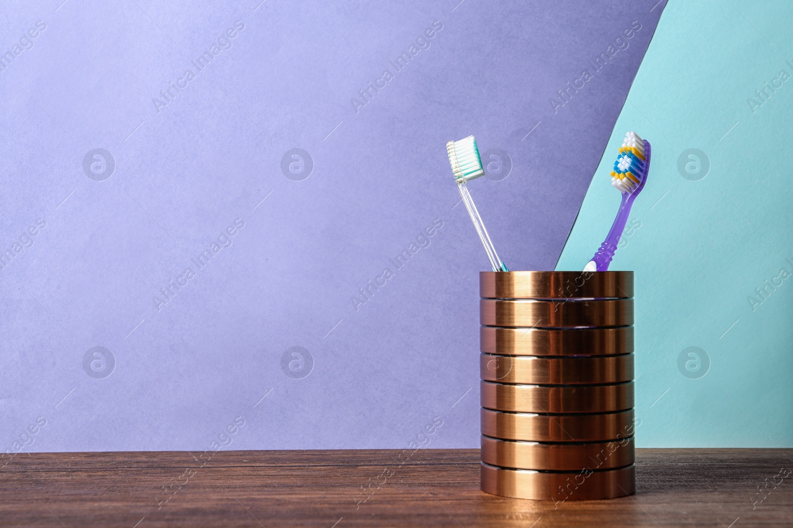 Photo of Cup with toothbrushes on table against color background. Dental care