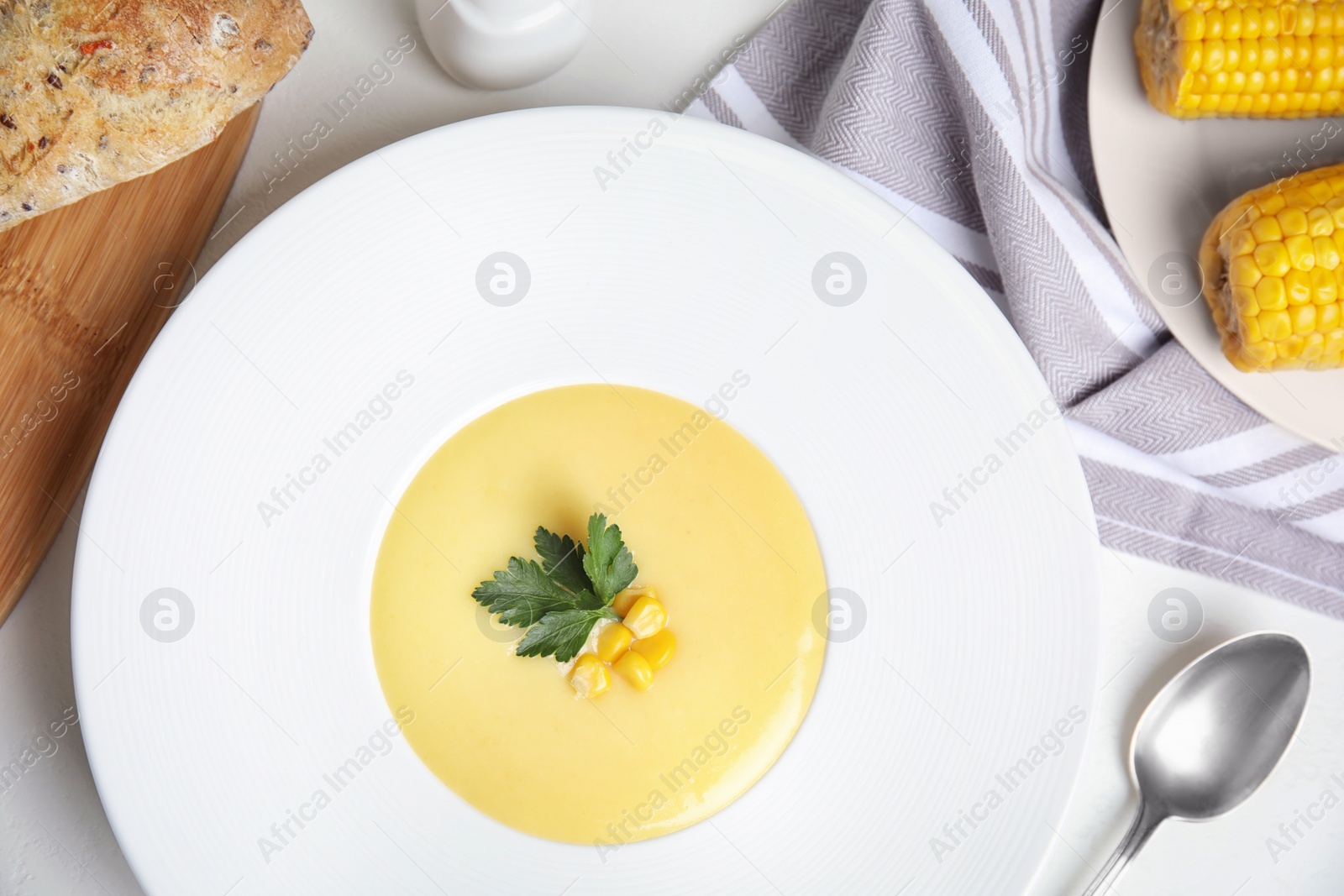 Photo of Delicious corn cream soup served on white table, flat lay