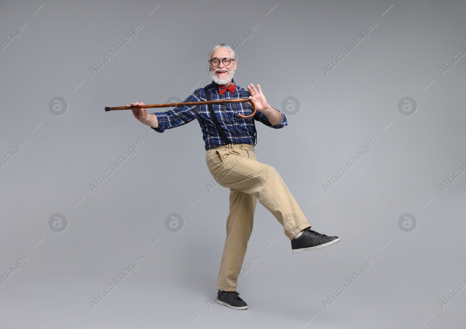 Photo of Cheerful senior man with walking cane on gray background