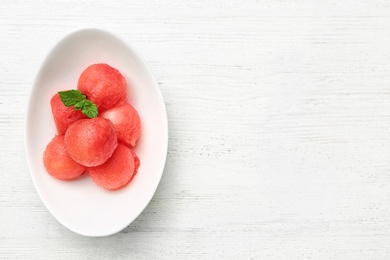 Photo of Plate of watermelon balls with mint on white wooden table, top view. Space for text