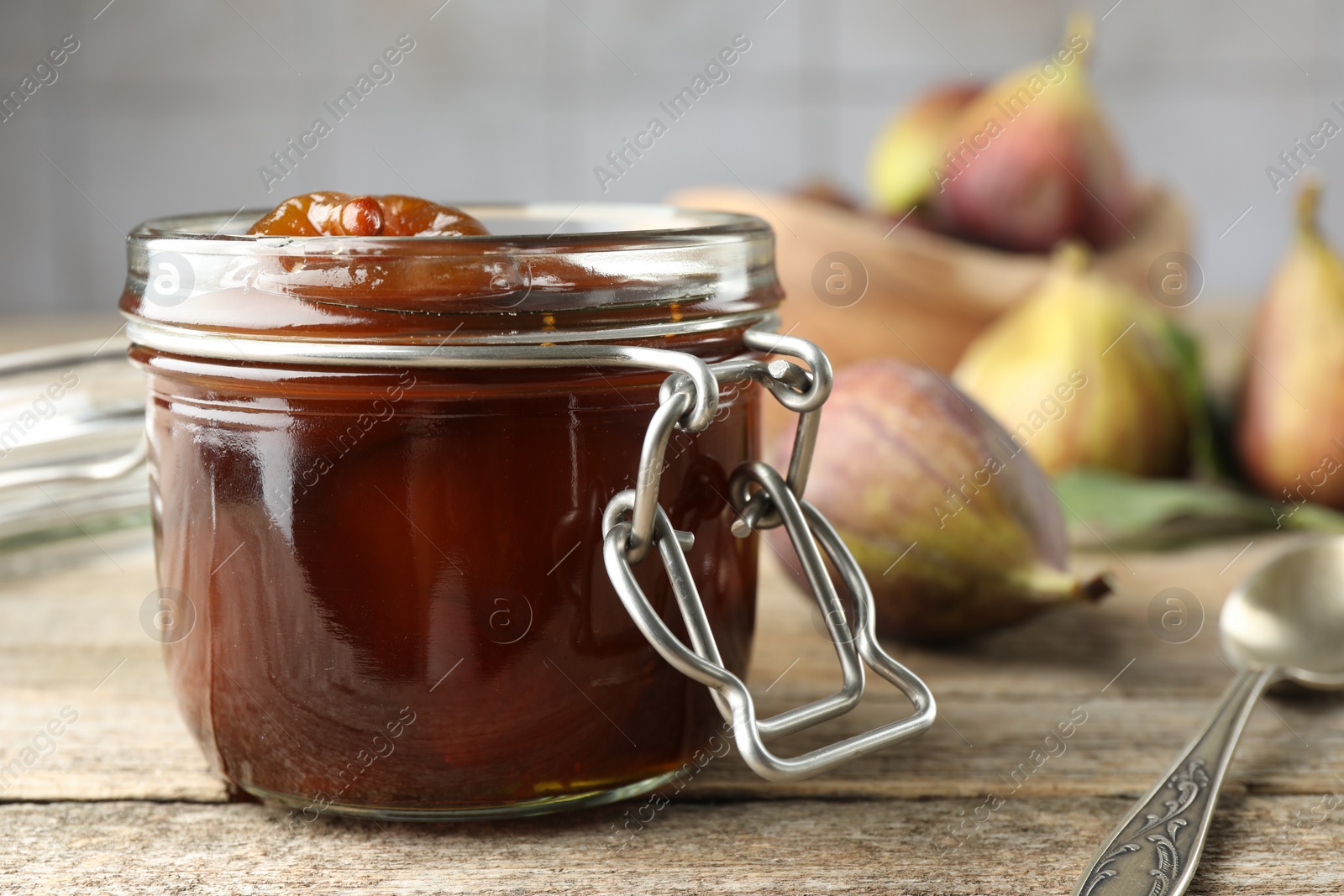 Photo of Jar of tasty sweet fig jam on wooden table