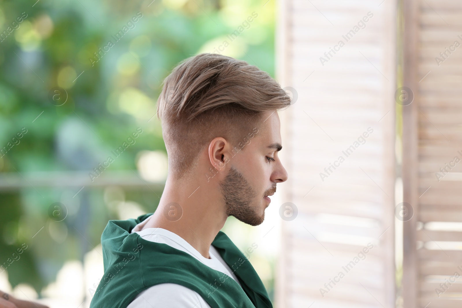 Photo of Young man with hairstyle of trendy color in barbershop