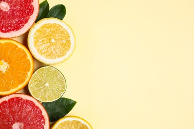 Photo of Different cut citrus fruits and leaves on beige table, flat lay. Space for text