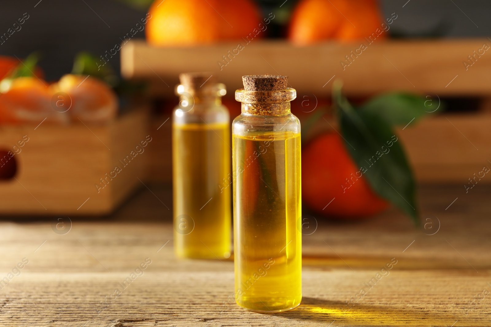 Photo of Bottles of tangerine essential oil on wooden table, closeup