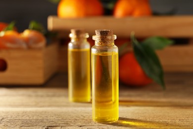 Bottles of tangerine essential oil on wooden table, closeup