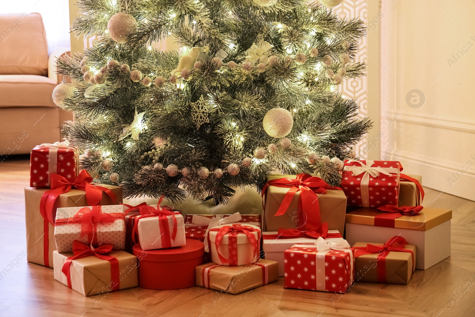 Photo of Pile of gift boxes near beautiful Christmas tree indoors