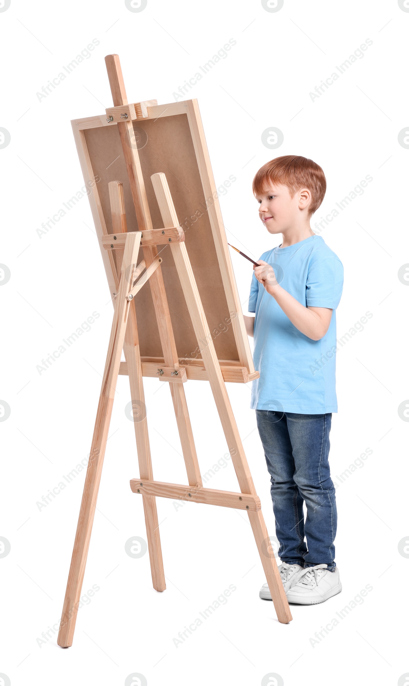 Photo of Little boy painting against white background. Using easel to hold canvas