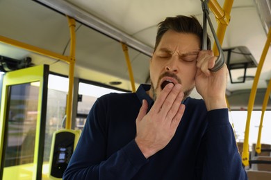 Sleepy tired man yawning in public transport