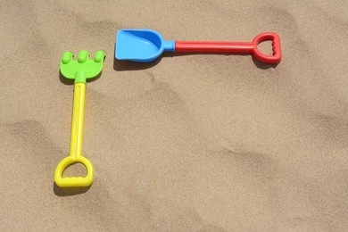 Photo of Plastic shovel and rake on sand, space for text. Beach toys