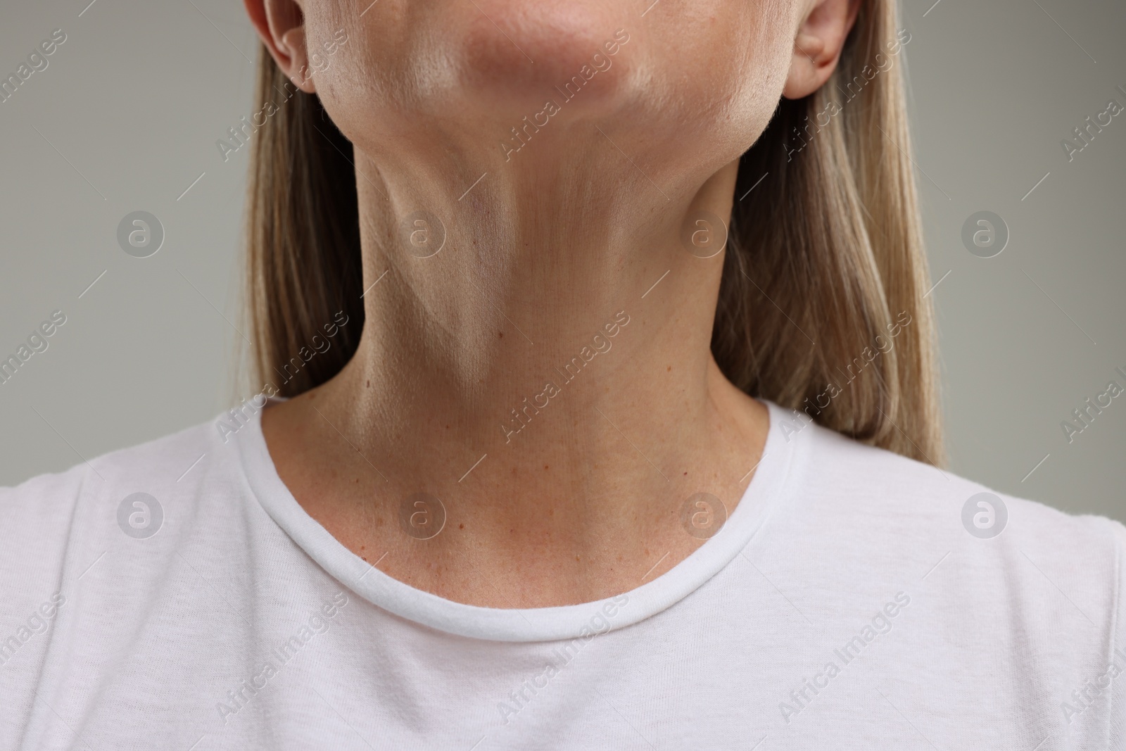 Photo of Mature woman showing her neck on grey background, closeup