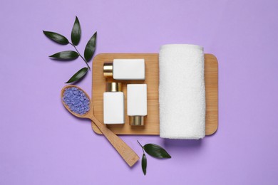 Photo of Spa layout with cosmetic and towel on violet background, flat lay