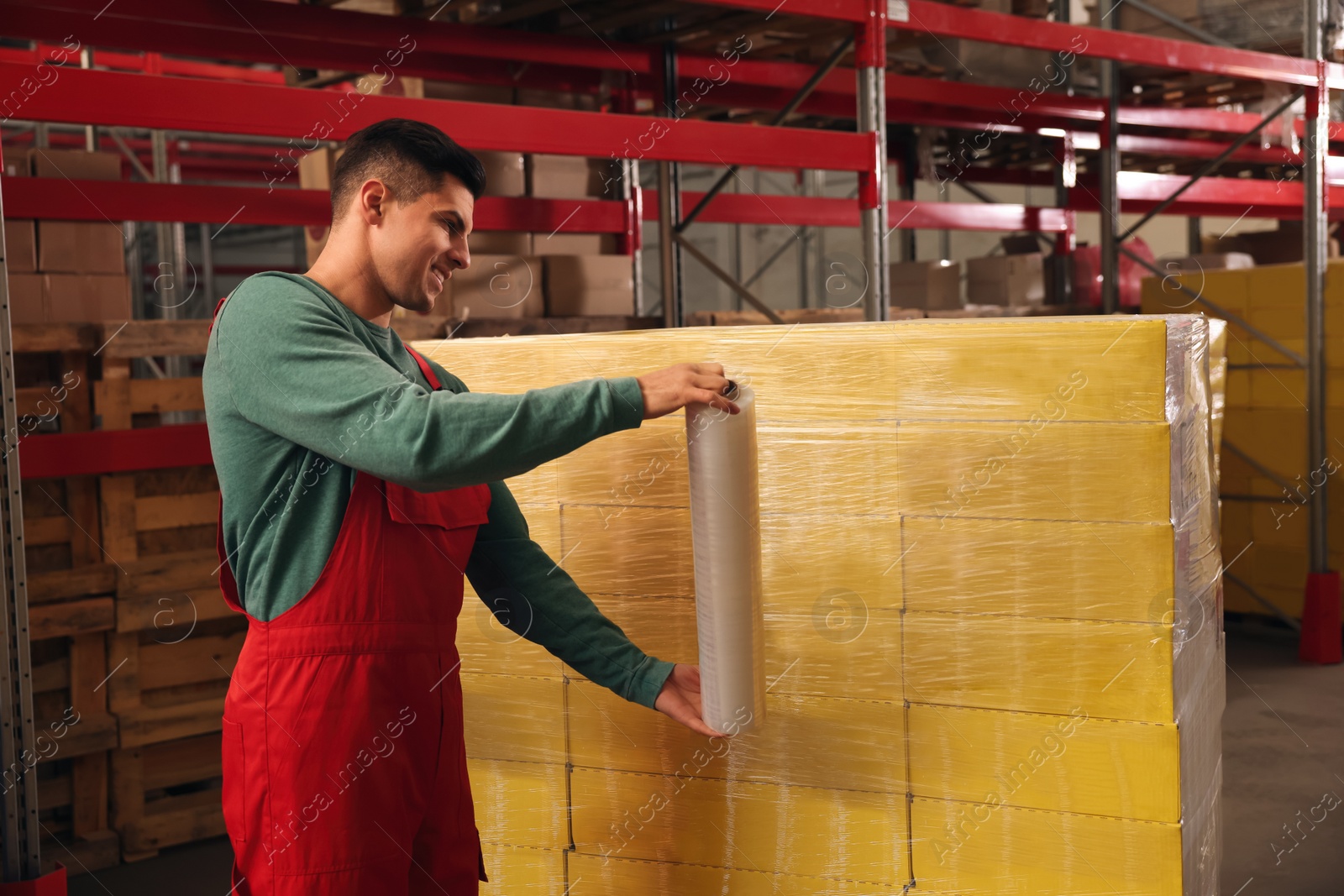 Photo of Worker wrapping boxes in stretch film at warehouse