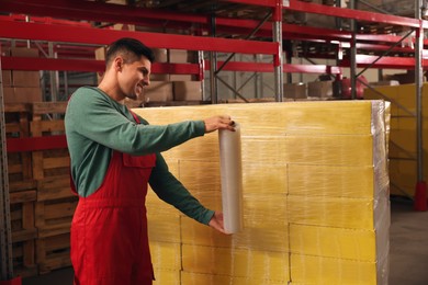 Worker wrapping boxes in stretch film at warehouse